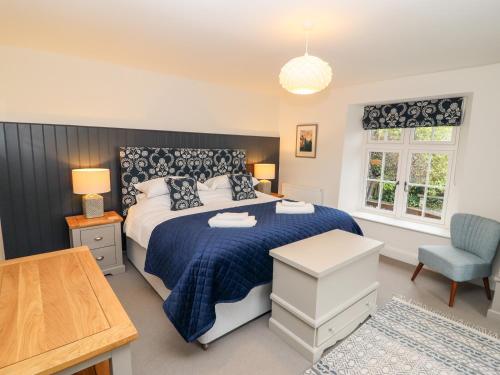 a bedroom with a bed with a blue blanket and a chair at Tilly's Cottage in Grasmere