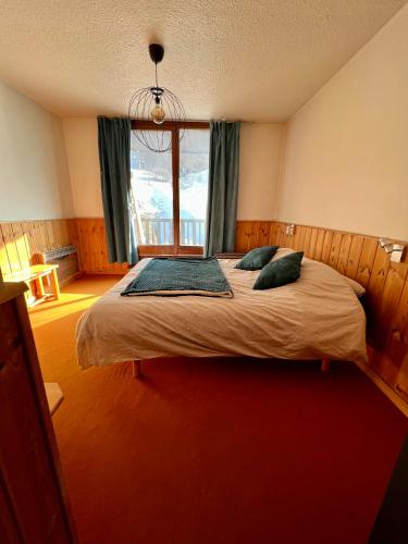 a bedroom with a large bed with a window at Carlines'home in Les Orres