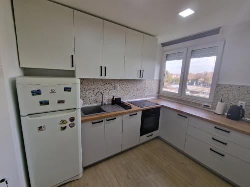 a kitchen with white cabinets and a white refrigerator at Studio SVACIC self check in in Osijek