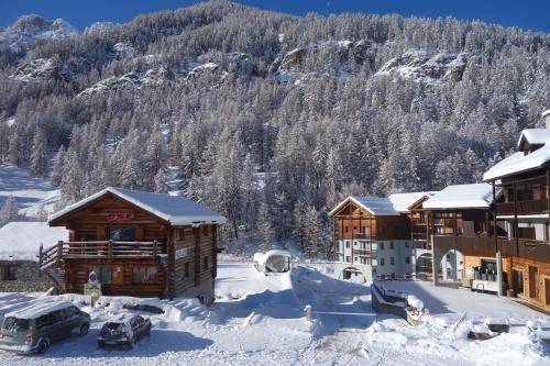 a lodge in the snow with cars parked in front at Skis aux pieds dans un appartement cosy au coeur du Queyras in Molines-en-Queyras