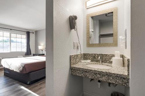 a bathroom with a sink and a bed in a room at Heritage Inn Express Chico in Chico