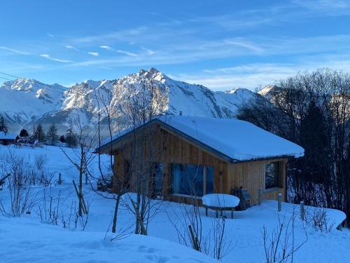 a cabin in the snow with mountains in the background at Chalet ski-in ski-out with jacuzzi in Nendaz in Nendaz