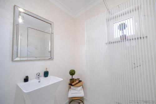 een witte badkamer met een wastafel en een douche bij Tesa Boutique Hotel in Tîrgu Neamţ