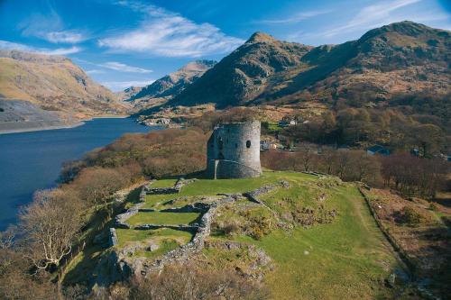 a castle on a hill next to a body of water at Prime location for Snowdon, Family and Dog friendly! in Llanberis