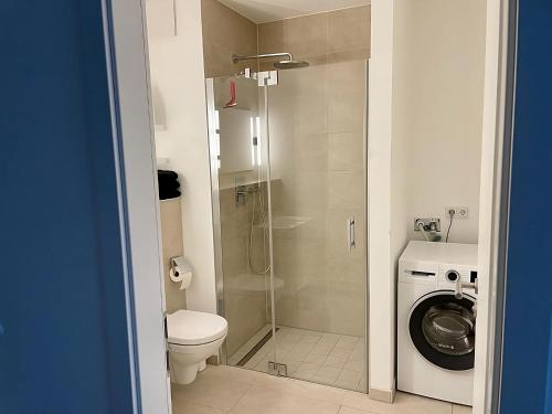 a bathroom with a shower and a toilet and a washing machine at Modern Apartment in the center of Munich in Munich