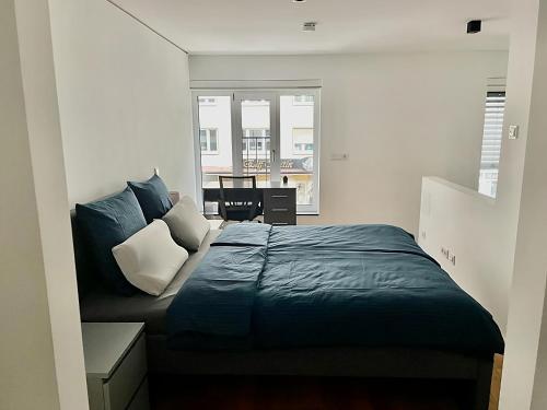 a bedroom with a bed with blue sheets and a window at Modern Apartment in the center of Munich in Munich
