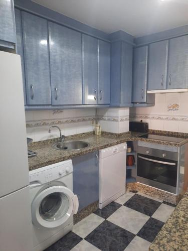 a kitchen with blue cabinets and a washing machine at Apartamento en casco histórico in Estepona