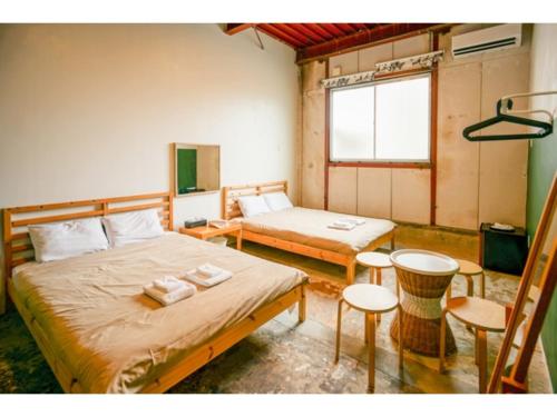 1 dormitorio con 2 camas, mesa y sillas en fan! -ABURATSU- Sports Bar & HOSTEL - Vacation STAY 78433v, en Nichinan