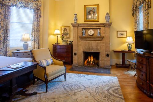a living room with a fireplace and a chair at The Gastonian, Historic Inns of Savannah Collection in Savannah