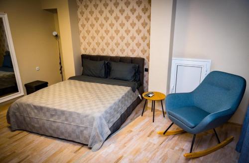 sypialnia z łóżkiem i niebieskim krzesłem w obiekcie Panorama Suites w mieście Plewen
