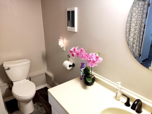 a bathroom with a toilet and a vase of flowers on a counter at Guest House with Private Entrance- walk to Downtown Noblesville in Noblesville