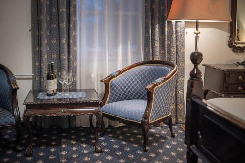a room with a chair and a table with a bottle of wine at Pytloun Old Armoury Hotel Prague, Stará Zbrojnice in Prague