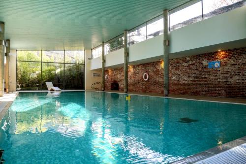 a large swimming pool with blue water in a building at The Ickworth Hotel And Apartments - A Luxury Family Hotel in Bury Saint Edmunds
