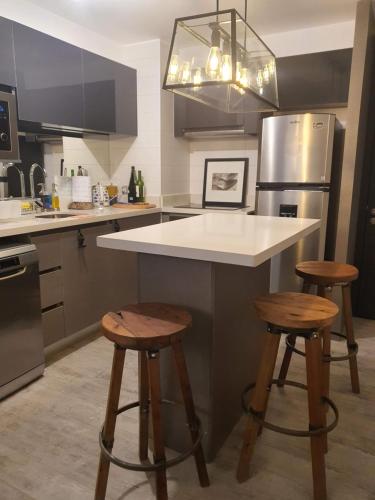 a kitchen with a island with two bar stools at Hermoso depto en Costa de Montemar, Vista al mar in Concón