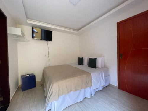 a hotel room with a bed and a tv at Pousada Areias do Pero in Cabo Frio