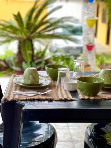 a table with green bowls and plates on it at Pousada Areias do Pero in Cabo Frio
