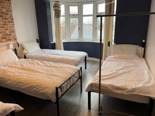 Habitación con 3 camas y ventana en Ovington Grove 2 fully equipped kitchen free parking 3 bedrooms Netflix, en Newcastle