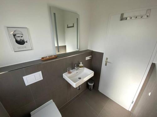 ein Badezimmer mit einem Waschbecken, einem WC und einem Spiegel in der Unterkunft Ferienhaus Karlsson mit Blick auf die Ostsee in Hohenfelde