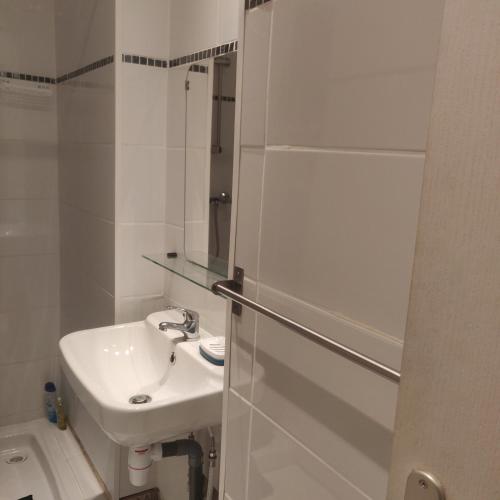 a white bathroom with a sink and a mirror at L'Avesnois in Fourmies