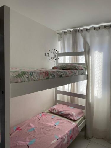 two bunk beds in a room with a window at Apartamento Pajuçara in Maceió