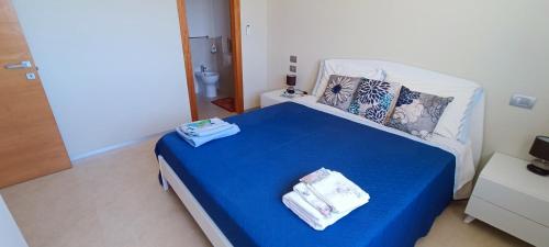 una camera da letto con un letto blu con asciugamani sopra di Dody's Home a Otranto