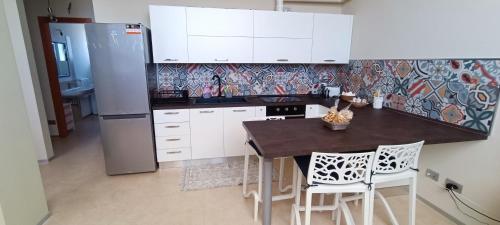 una cucina con mobili bianchi, tavolo e sedie di Dody's Home a Otranto