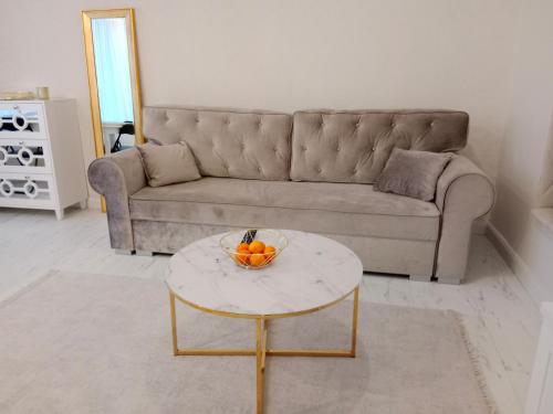 a living room with a couch and a bowl of oranges on a table at Apartament Glamour Chełm in Chełm