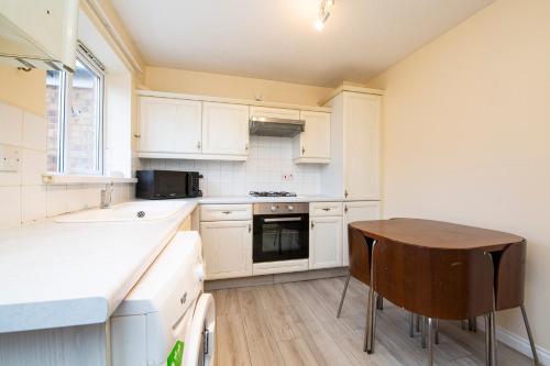 uma cozinha com armários brancos e uma mesa de madeira em Durham Home Away from Home em Durham