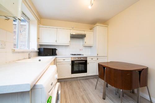 a kitchen with white cabinets and a wooden table at Durham Home Away from Home in Durham