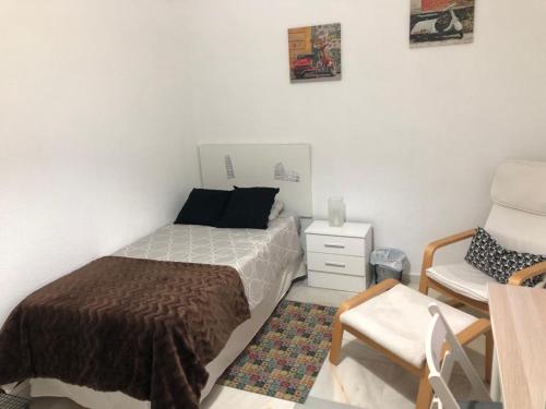 1 dormitorio pequeño con 1 cama y 1 silla en Tablada Los Remedios, en Sevilla