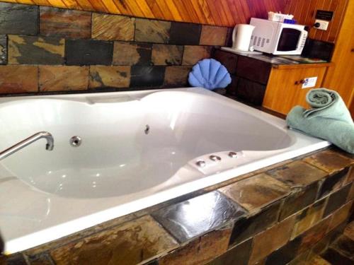 a large bath tub in a room with a microwave at Pelicans Motel San Remo in San Remo