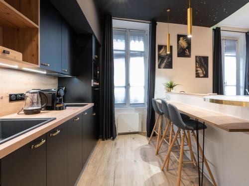 une cuisine avec des placards noirs et un comptoir avec des tabourets dans l'établissement Appartement chic proche Bellecour avec parking, à Lyon