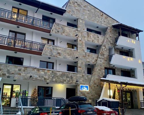 a large building with cars parked in front of it at Luxury Aparthotel STUDENETS in Pamporovo