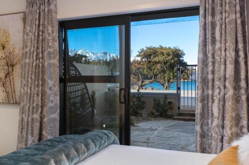 a bedroom with a sliding glass door with a view at TAHUNA LAKEFRONT LUXURY, Central Location in Queenstown