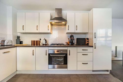 uma cozinha com armários brancos e um forno com placa de fogão em Anox serviced apartment em Newcastle upon Tyne