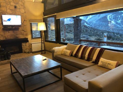 a living room with a couch and a table and a tv at Casas De Montaña Las Leñas Los Molles in Los Molles