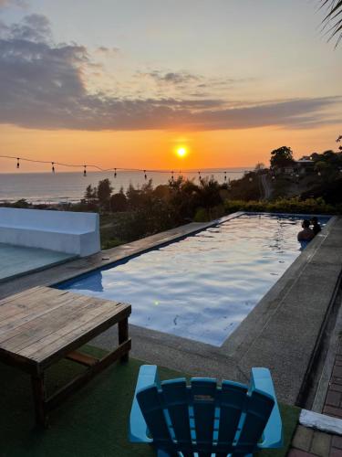 um pôr-do-sol sobre uma piscina com mesa e cadeiras em Punta Hills Montanita em Montañita