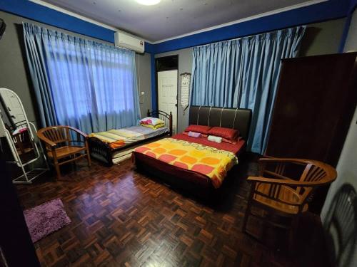 a bedroom with a bed and chairs in a room at Homestay Petrajaya Kuching in Kuching