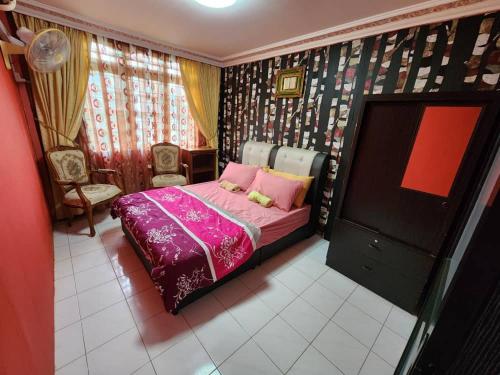 a bedroom with a bed with pink sheets and a tv at Homestay Petrajaya Kuching in Kuching