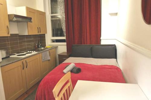 a small kitchen with a bed with a red blanket at Private London Kensington studio 2 mins from tube in London