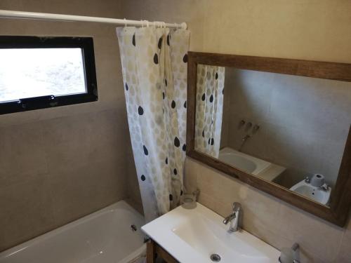 a bathroom with a tub and a sink and a mirror at Casas De Montaña Las Leñas Los Molles in Los Molles