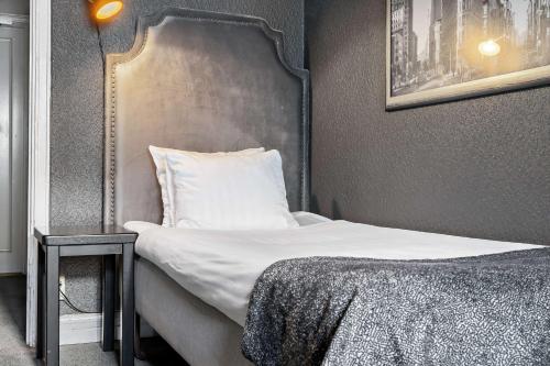 a bedroom with a bed with a headboard and a table at Centric Hotel in Norrköping
