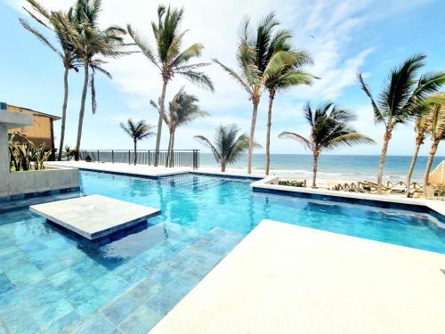 a swimming pool with palm trees and the beach at Condominio, Las Pocitas de Máncora- Deluxe in Máncora