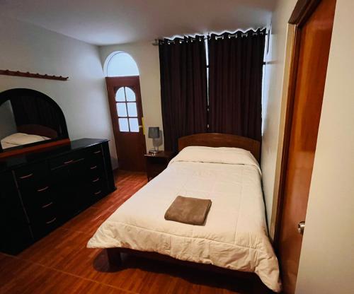 a bedroom with a bed and a dresser at Hotel Baños del Inca in Los Baños del Inca