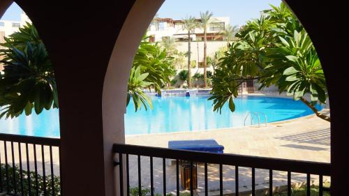 een balkon met uitzicht op een zwembad bij Ground floor apartment by circular pool in Talabay (sweet coffee apartment) in Aqaba