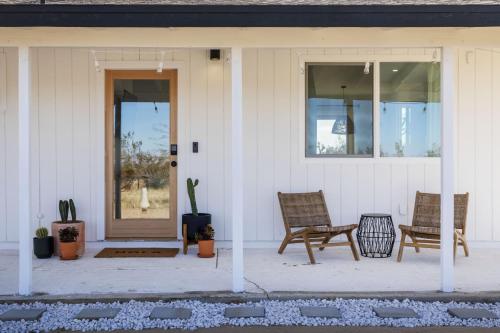 a porch with two chairs and a bench on a house at Mojave Mesa - Desert Views & Desert Style home in Yucca Valley