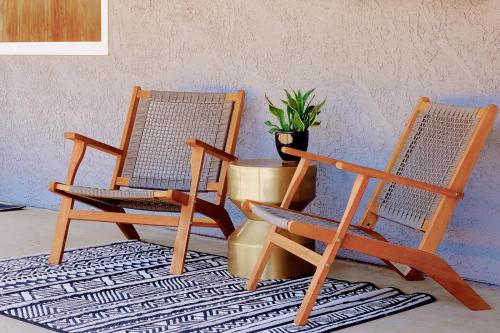 two rocking chairs and a potted plant on a rug at Live Centered with Hot Tub, Fire Pit In Joshua Tree home in Joshua Tree