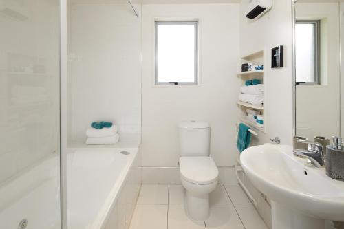 a white bathroom with a toilet and a sink at FYFFE on Riccarton in Christchurch