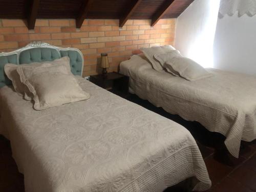1 dormitorio con 2 camas y pared de ladrillo en Bella casa de campo, con Hidrospa y zonas verdes, en Piedecuesta