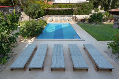 een uitzicht over een zwembad met drie banken bij Villa Mediterranea in Bol